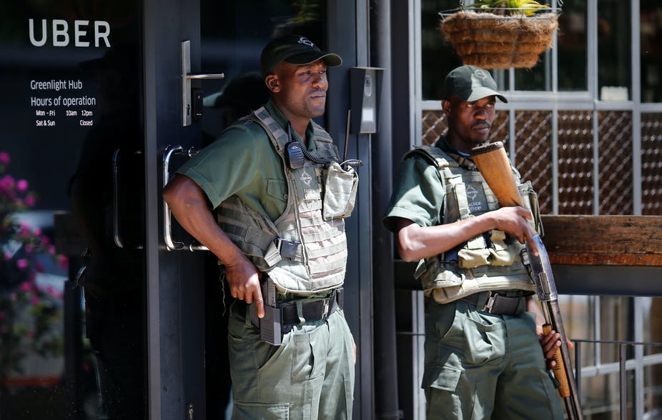 Two African private security guards holding their guns, protecting a private business