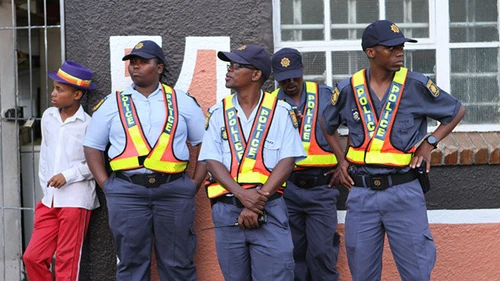 African man standing with four South African police officers infront of building